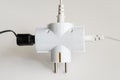 Tree plugs socketed into white electric splitter on a white background. Splitter for simultaneous switching of three electrical