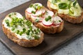 Tree sandwiches with fresh radish microgreens and cream cheese on grey background. Close up