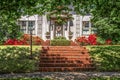 Tree shaded dappled sidewalk and sloped lawn in front of upscale stucco house with wreath and azaleas and brick steps - beautiful Royalty Free Stock Photo