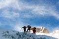 Three snow hikers climbing a snowy mountain during a snowstorm