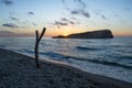 A tree stump on the beach and behind it an island at sunset, the Mediterranean Sea Jijel Algeria, Africa island. Royalty Free Stock Photo