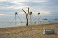 Tree Trunk Connected With Wooden Chair For Photoshootings On A Sand Beach With Elephant Sculptures And Boats In The Sea In Phu