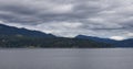 Treed Island with Homes and ferry passing by, surrounded by ocean and mountains. Royalty Free Stock Photo