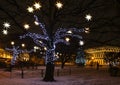 Trees decorated with garlands and glowing stars in a square in the city. New Year and Christmas mood in town Royalty Free Stock Photo