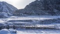 Trees grow in a snowy valley and along the bed of a frozen river. Royalty Free Stock Photo