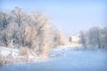 Trees and a house on the bank of a blue river in a white snowy frost in the Moscow region