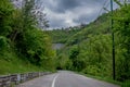 Trees Surrounding a Mountain Road Turn Below Epic Sky With Clouds