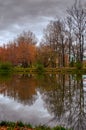 Trees with yellow and red leaves on the banks of the pond in the autumn park are reflected in the water. Royalty Free Stock Photo