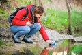 Trekker filling water bottle of raw water in a river.