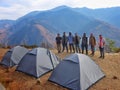 Trekker friends posing for group photo at Naag Tibba basecamp, Uttarakhand. Camps and majestic mountains form a stunning backdrop