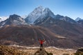 A trekker standing on rock and looking to Ama Dablam mountain peak in Dingboche village, Everest base camp trekking route, Nepal