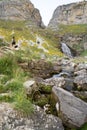 trekker woman and her dog approaching a river waterfall in Ordesa National Park, in the Spanish Pyrenees