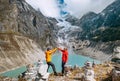 Trekkers couple dressed bright waterproof jackets giving High Five enjoying glacier falling in high altitude Sabai Tso glacial