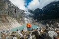 Trekkers couple dressed bright waterproof jackets hug on rock enjoying glacier falling in high altitude Sabai Tso glacial lake cca