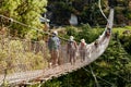 Trekkers and Sherpa crossing a suspension iron bridge.