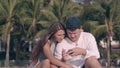 Tremendous couple sits under bright sunlight against palms