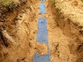 Trench with blue plastic protection tape. Marked of cables under clay during building of internet