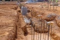 The trench for the concrete foundation is reinforced with steel bars and rebar wires at the construction site as part of