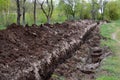 A trench dug in the park by utilities to lay pipes for the water supply of the population. A large ditch made for laying wires on Royalty Free Stock Photo