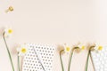 Trending minimalistic flat design of a blogger\'s workplace. Notepad, pen and bouquet of daffodils with copy space