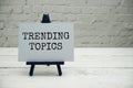 Trending Topics text on white brick wall and wooden background