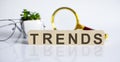 TRENDS concept on wooden cubes and flower ,glasses ,coins and magnifier on the white background