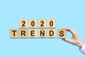 2020. Trends. Female hand makes up words from wooden blocks. Isolated on a blue background. New Year Trends Concept. B Royalty Free Stock Photo