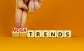 Trends or megatrends symbol. Businessman turns cubes and changes words trends to megatrends. Beautiful orange table, orange