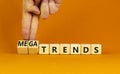 Trends or megatrends symbol. Businessman turns cubes and changes words trends to megatrends. Beautiful orange table, orange