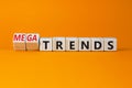 Trends or megatrends symbol. Turned wooden cubes and changed words trends to megatrends. Beautiful orange table, orange background