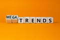 Trends or megatrends symbol. Turned wooden cubes and changed words trends to megatrends. Beautiful orange table, orange background