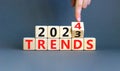 2024 trends new year symbol. Businessman turns a wooden cube and changes words Trends 2023 to Trends 2024. Beautiful grey table