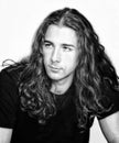 Stylish male model with long wavy hair posing in studio. Trends, style, fashion concept.