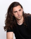 Stylish male model with long wavy hair posing in studio. Trends, style, fashion concept. Royalty Free Stock Photo