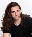 Stylish male model with long wavy hair posing in studio. Trends, style, fashion concept.