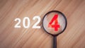 2024 trends.Top view of a magnifying glass is placed on a wooden table with the numbers 2024 inside. 2024 goal concept. . Royalty Free Stock Photo