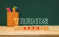 Trends 2019 on wood cube with colorful pen box on wood table with green blackboard wall.education future concept Royalty Free Stock Photo