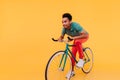 Trendy african man in white sneakers posing emotionally on bike. Indoor portrait of enthusiastic sp Royalty Free Stock Photo