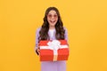 trendy amazed kid in sunglasses and suit hold present box on yellow background, present Royalty Free Stock Photo