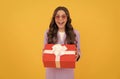 trendy amazed kid in sunglasses and suit hold present box on yellow background, present Royalty Free Stock Photo
