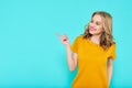 Trendy attractive young woman wearing mustard color summer dress posing over pastel blue background. Front view of smiling woman.