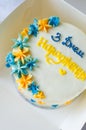 Trendy bento cake with with an blue-yellow inscription in Ukrainian "happy birthday" on light background