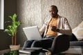 Trendy Black african creative writer sitting, relaxing and typing on laptop.