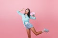 Trendy black-haired woman with suntan dancing with pink longboard and laughing. Sporty asian girl in blue shirt and Royalty Free Stock Photo