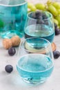 Trendy blue moscato wine in glass and in bottle, green and red grape on background, vertical Royalty Free Stock Photo