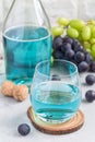 Trendy blue moscato wine in glass and in bottle, green and red grape on background, vertical Royalty Free Stock Photo