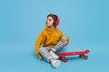 Stylish youngster listening to music near longboard