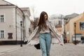 Trendy brown-haired young woman in fashionable spring clothes with a leather stylish black bag walks on the street near vintage Royalty Free Stock Photo