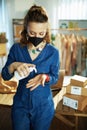 Trendy business owner woman disinfecting hands in office