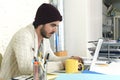 Trendy businessman in cool hipster beanie with coffee working busy at modern home office with compute Royalty Free Stock Photo